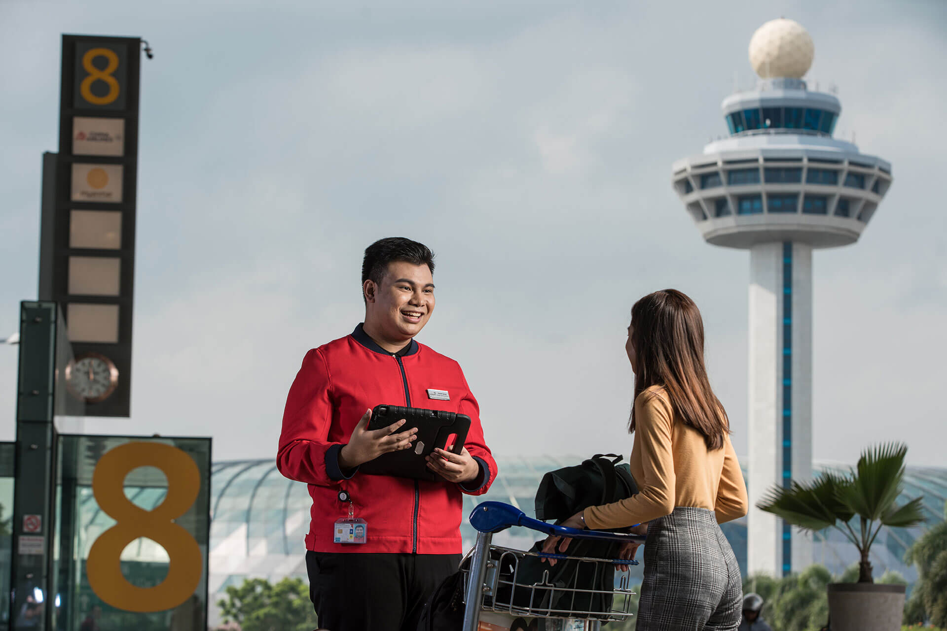An RP student intern guiding passengers at the entrance of Changi Airport