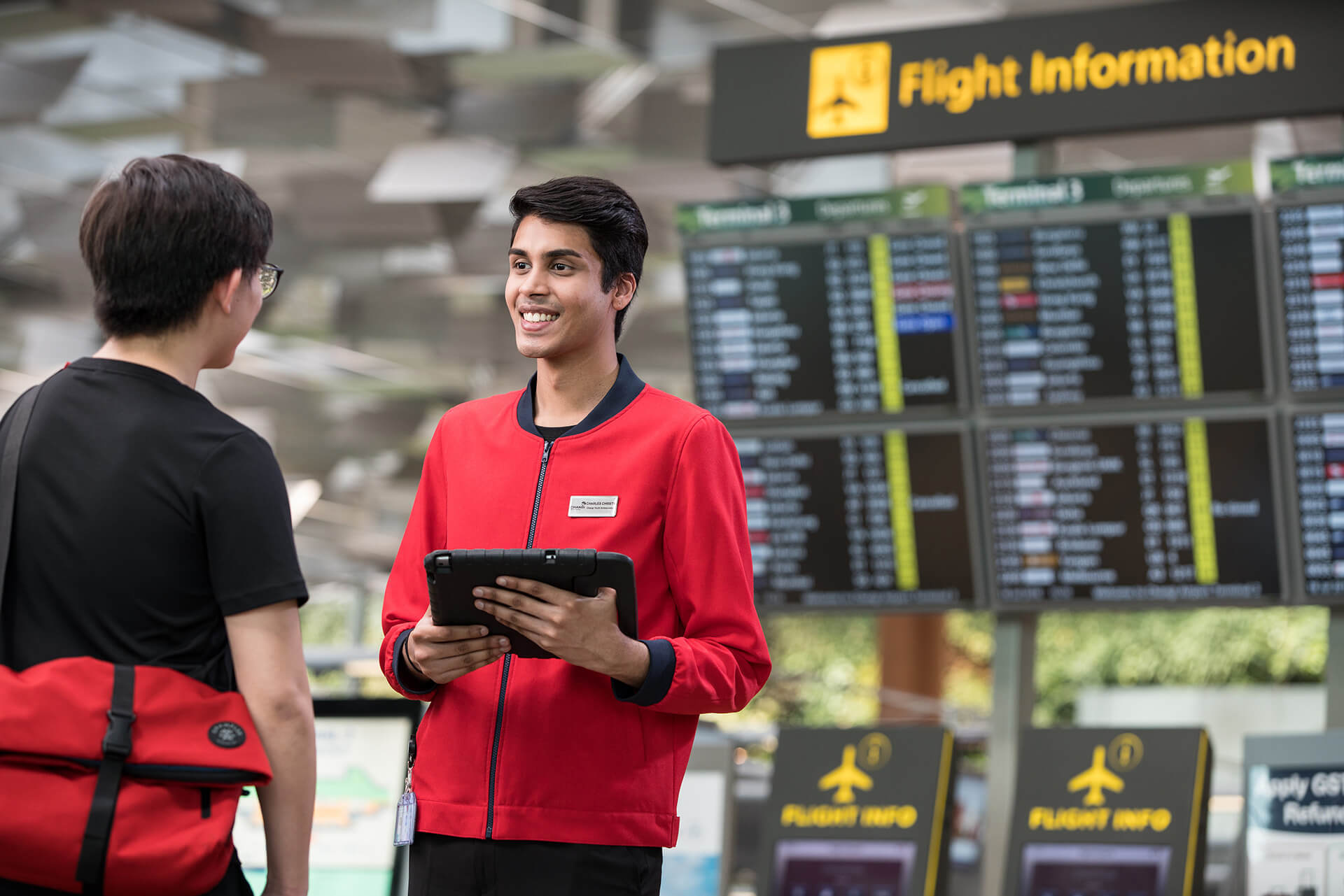 A student airline intern guiding a passenger in Changi Airport