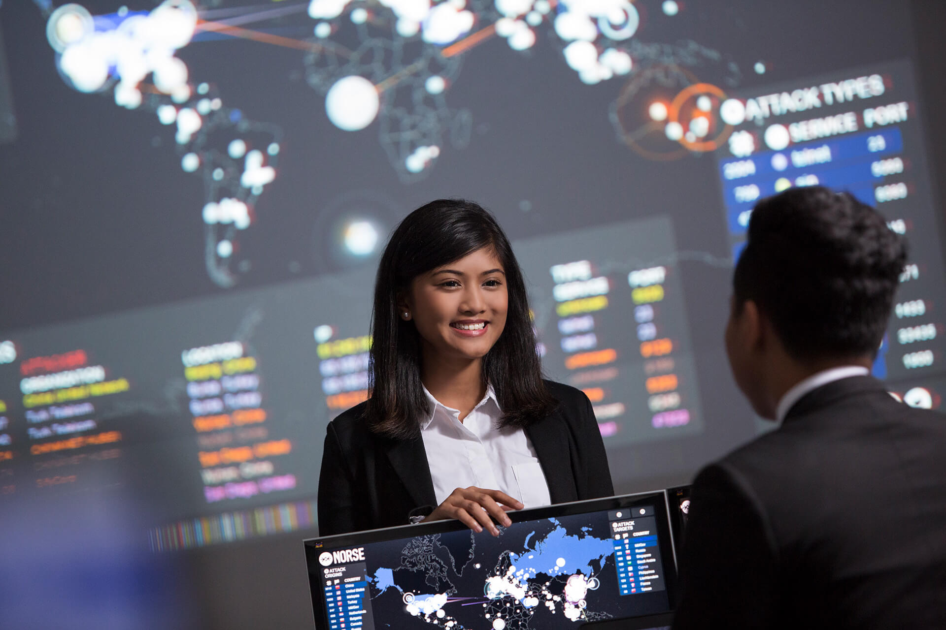 A female professional conversing with her colleagues with high tech dashboards in the background