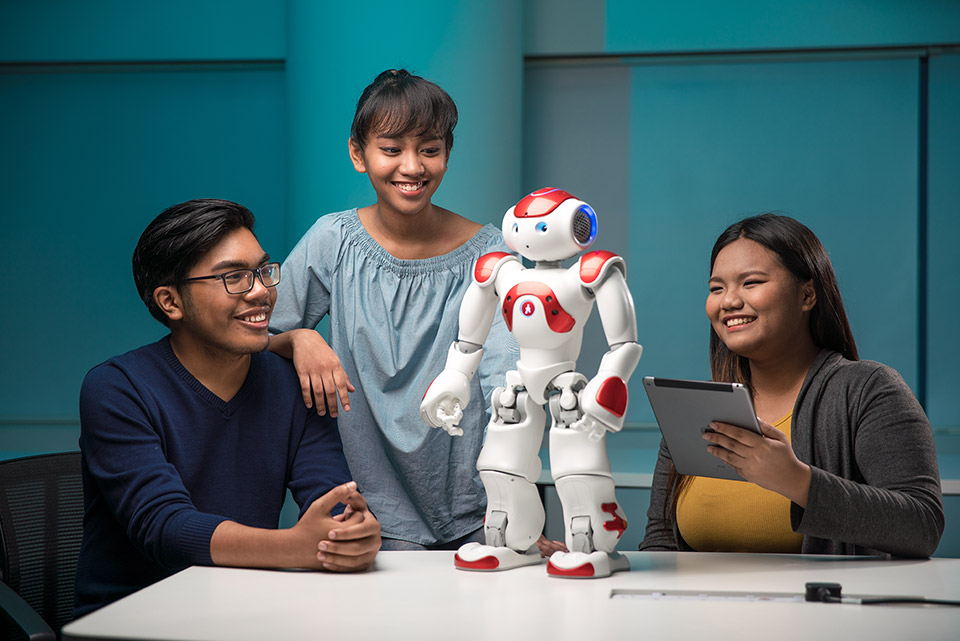 A group of students programming a high-tech robot in a modern classroom