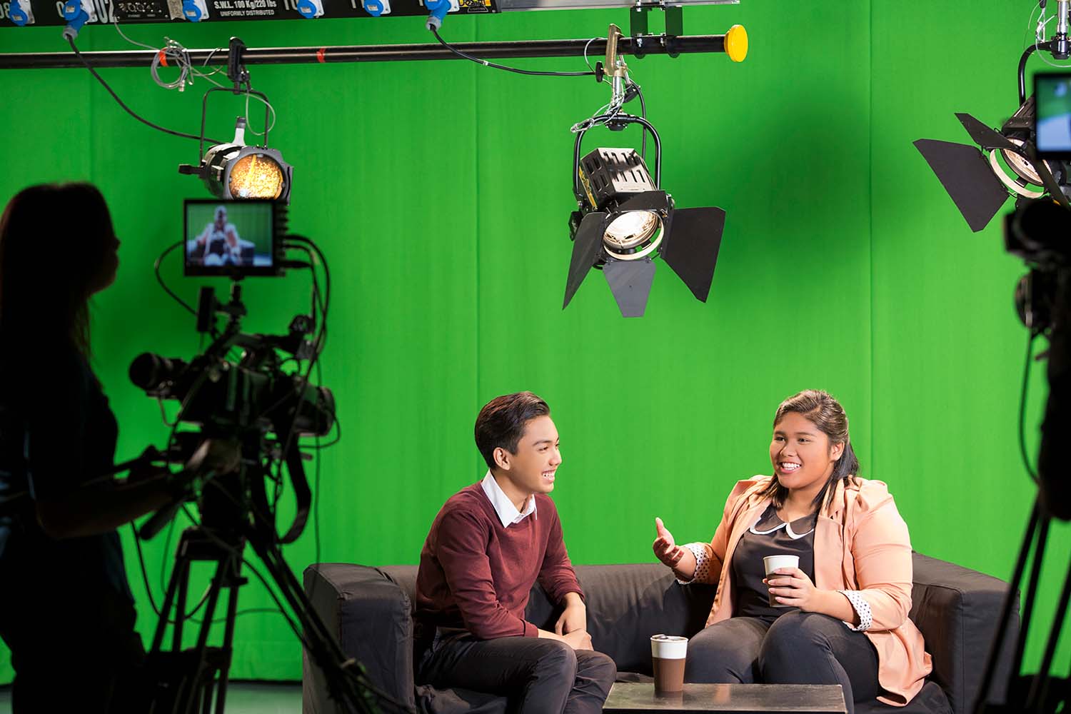 Two students interacting at a talk show, filmed on set at a production studio