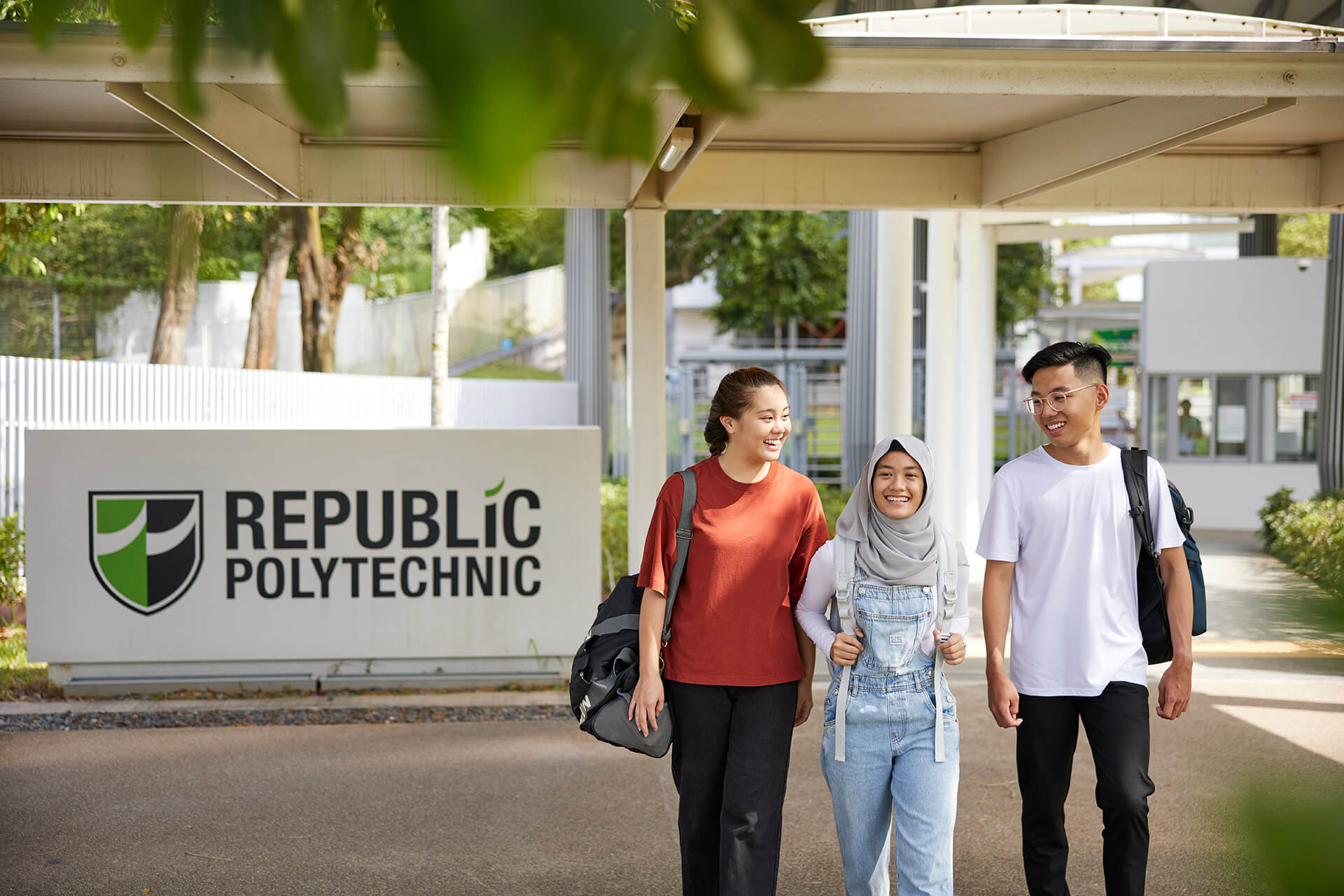 Three students walking back home, with the Republic Polytechnic signage visible in the background