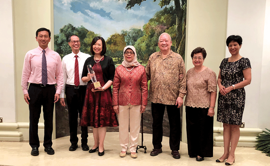 Ms. Ella Siu receiving her award from President Halimah Yacob at the Istana