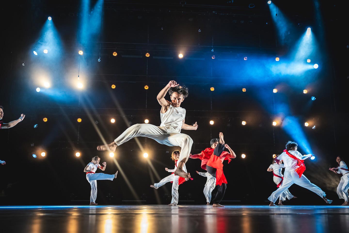 A student performer doing a high-energy kick on stage